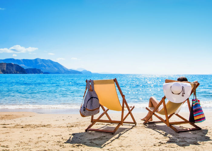 Person sunbathing on yellow beach chair on empty beach