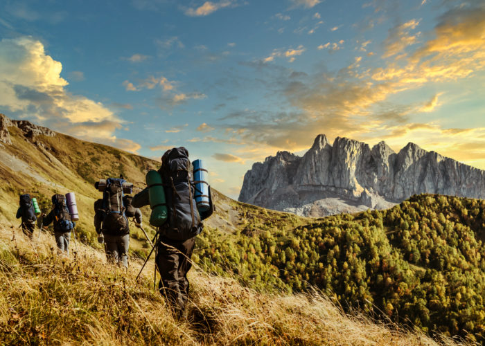 Line of hikers making their way up a mountain path with hiking sticks and backpacks