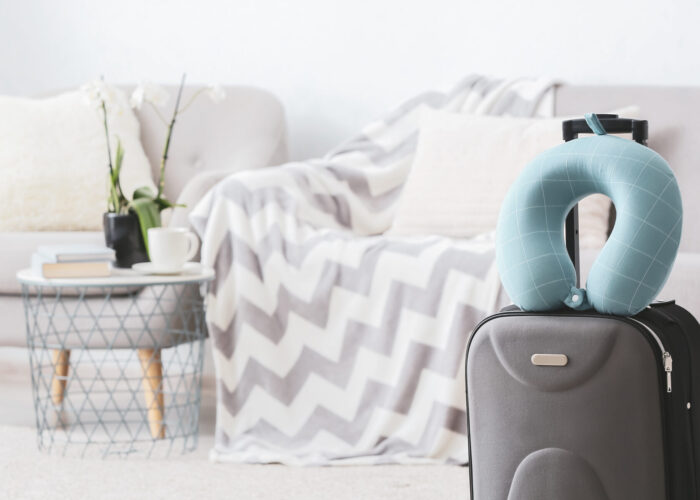 Travel neck pillow on top of rolling suitcase in light colored living room