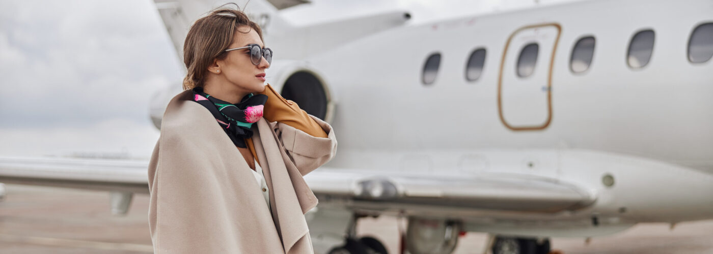 Well-dressed woman standing next to a jet plane