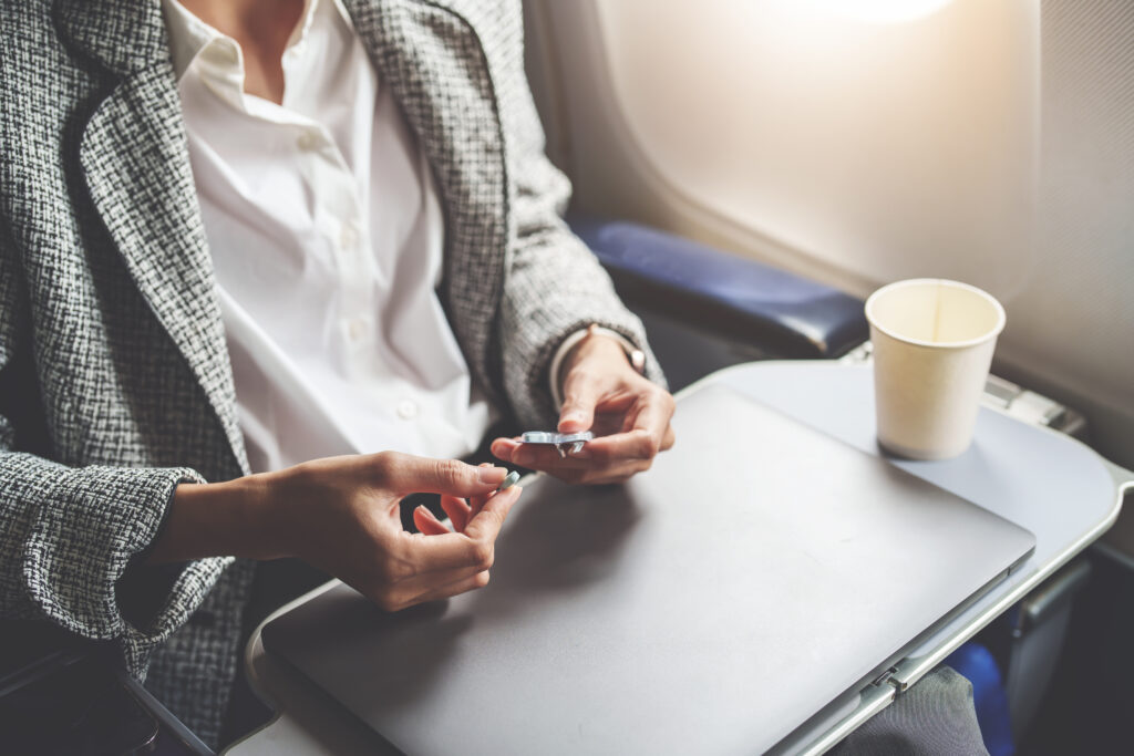 Close up of person taking a pill from a blister pack on a plane