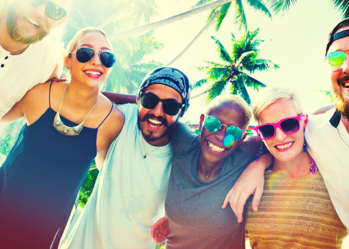 Friends on beach smiling and wearing sunglasses