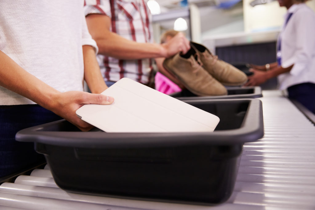 Person placing tablet into bin at airport security