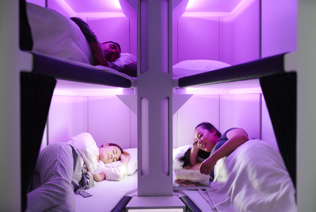 People resting in Sky Nest, lay-flat economy seats on Air New Zealand that resemble bunk beds