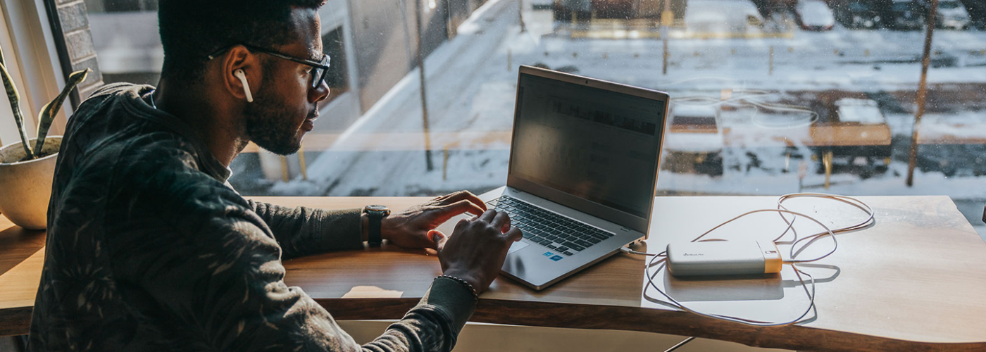 Man working in cafe with laptop plugged into a BioLite Charge Series portable charger