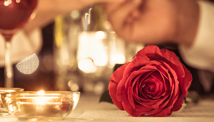 Couple holding hands across candlelit dinner table